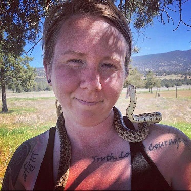 Horse advocate Ren Hurst smiling at camera with small snake behind her neck and on shoulder